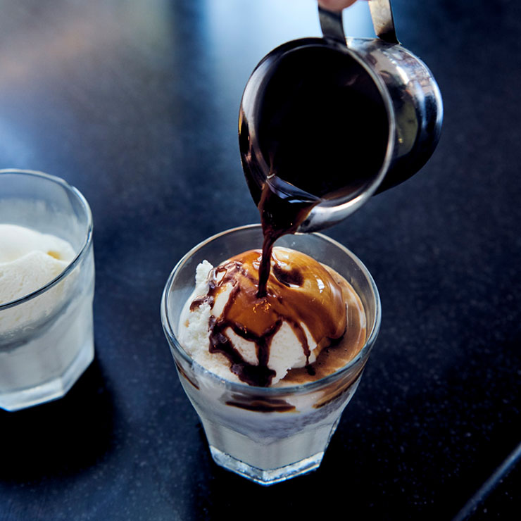 Espresso shot being poured over ice cream in a glass on a counter